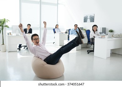 Excited Office Manager Sitting In Beanbag In Center Of The Office