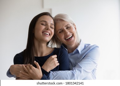Excited overjoyed beautiful aged lady and her grown-up daughter cuddling and laughing remembering happy moments of young female childhood, mother and daughter-in-law having perfect relations