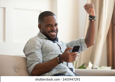 Excited overjoyed black man winner holding smartphone feeling euphoric with mobile online bet bid game win, happy ecstatic african guy looking at cell phone celebrate receiving reading good news
