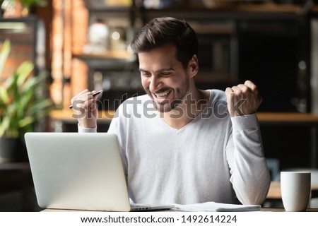 Excited overjoyed young business man student winner looking at laptop celebrate bet bid win online success victory new opportunity sit at cafe table, read good internet email news, got new job offer