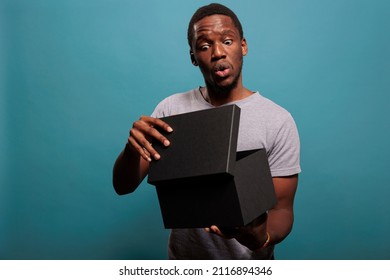Excited person feeling surprised after unpacking gift box and opening to see delivery order. Shocked man unboxing package present from postal delivery service, enjoying shopping surprise.