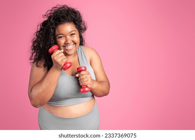 Excited plus size black woman in sportswear holding dumbbells and laughing, standing on pink studio background, copy space. Workout for body care, weight loss - Powered by Shutterstock