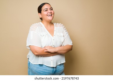Excited plus size woman laughing and having fun feeling positive emotions in front of a studio background