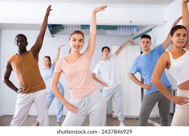 Excited positive diverse men and women of different ages stretching before modern dancing class in school for adults - Powered by Shutterstock