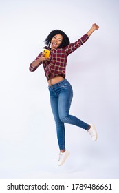 excited pretty young black woman holding her phone jumps in excitement
