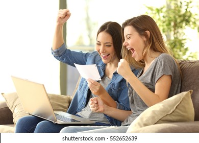 Excited roommates reading a bank notification sitting on a sofa in the living room at home