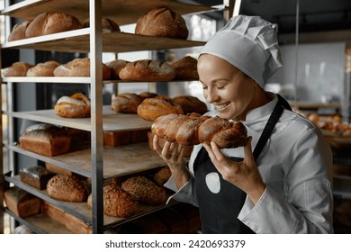 Excited satisfied female baker smelling fresh bread in bakerhouse kitchen - Powered by Shutterstock