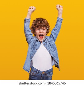 Aufgeregter Schüler in zwangloser Abnutzung mit Fäusten auf gelbem Hintergrund beim Schreien und Feiern der Leistung