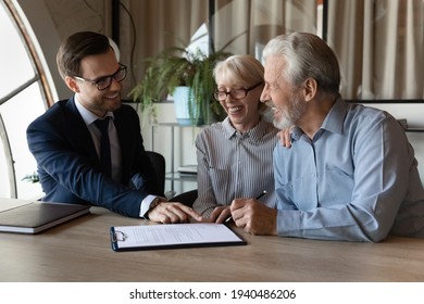 Excited senior couple buyers sign paper contract buy house or apartment from smiling male realtor or broker. Happy mature man and woman spouses make deal put signature on agreement. Rent concept.