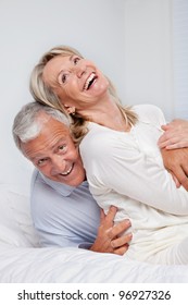 Excited Senior Couple Laughing Together On Bed