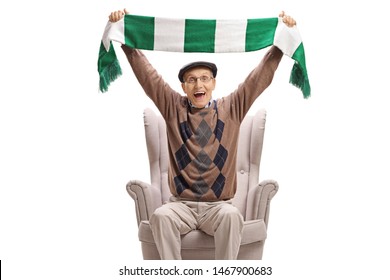 Excited Senior Man In An Armchair Cheering With A Scarf Isolated On White Background