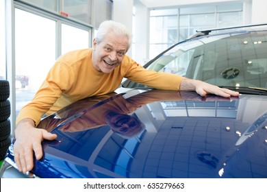 Excited Senior Man Smiling Joyfully Hugging His Newly Bought Automobile At Car Dealership Copyspace Offer Discount Selling Price Insurance Rental Travelling Retiring Retirement Sales Transportation