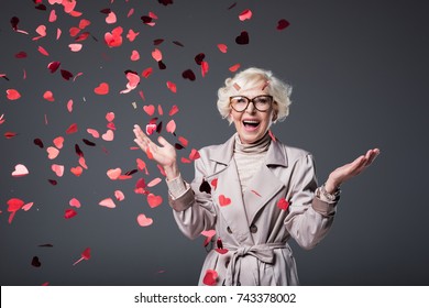 Excited Senior Woman With Heart Shaped Confetti On St Valentines Day, Isolated On Grey