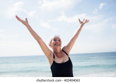 Excited senior woman standing on beach on a sunny day