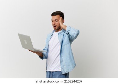 Excited shocked tanned handsome man in casual basic t-shirt have operation problems with laptop touch temple posing isolated on over white background. Copy space Mockup. Electronics repair IT concept