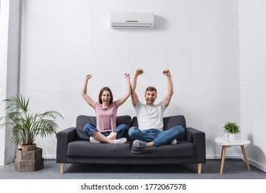 excited shouting couple at home with air conditioner