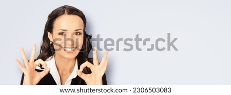 Excited smile positive businesswoman wear black confident suit show make ok okay hand sign, isolated on light grey gray wall background. Happy gesturing brunette woman. Business success concept. Wide.