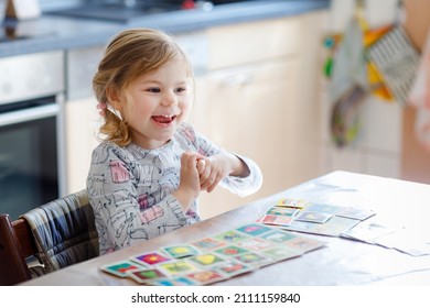 Excited Smiling Cute Toddler Girl Playing Picture Card Game. Happy Healthy Child Training Memory, Thinking. Creative Indoors Leisure And Education Of Kid. Family Activity At Home.