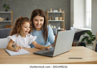 Excited Smiling Mother And Little Child With Pencil Sitting At Table At Home, Looking At Screen Of New Laptop Computer, Learning Online, Having Fun Interesting Class, Doing Homework With Private Tutor