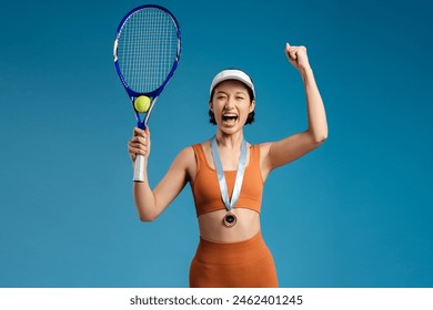 Excited smiling woman, competition winner in gold medal holding tennis racket and looking at camera standing isolated on blue background. Concept of victory, sport - Powered by Shutterstock