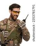 Excited soldier in armor vest, talking on walkie talkie in studio. Portrait of smiling infantryman in uniform and glasses, using portable radio, reporting, isolated on white. Army, connection concept.