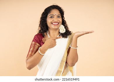 Excited South Indian woman pointing finger for advertisement isolated on beige background, blank space for promotion, look here. - Shutterstock ID 2216519491