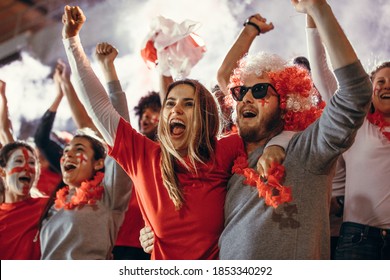 Excited sports fans at live game chanting and cheering for their team. Young people watching football match chanting to cheer English national team.