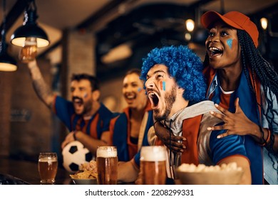Excited sports fans watching football match on TV and shouting after the winning goal of their favorite team during the world cup. - Shutterstock ID 2208299331
