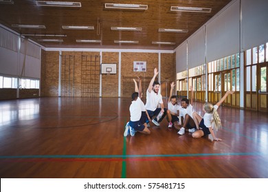 Excited Sports Teacher And School Kids Playing In Basketball Court At School Gym