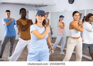 Excited sporty multiracial people practicing new movements steps during dancing training in studio - Powered by Shutterstock