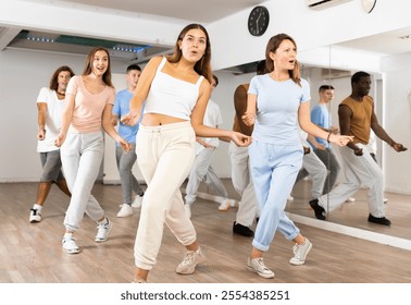 Excited sporty multiracial people practicing new movements steps during dancing training in studio - Powered by Shutterstock