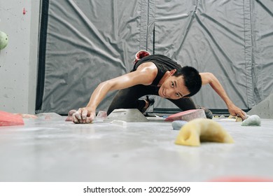 Excited ssweaty trong fit man climbing up the boulderingwall, view from above - Powered by Shutterstock