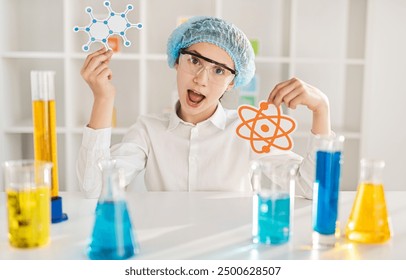 Excited student in a school chemistry class holding molecular and atomic models with lab equipment on the table. Learning and discovery. - Powered by Shutterstock