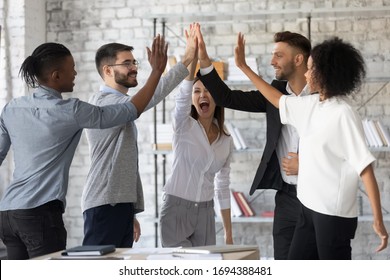Excited Successful Multiracial Business People Giving High Five, Celebrating Win. Good Teamwork Result Concept. Happy Employees Team Engaged In Team Building Activity At Corporate Meeting.