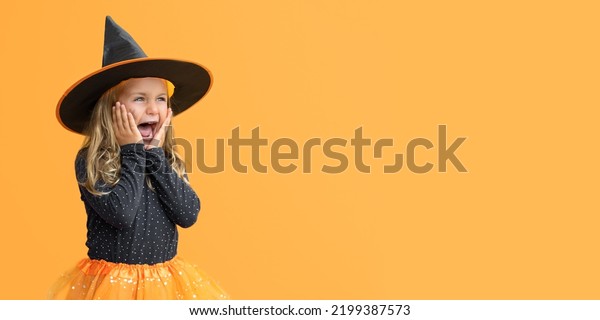 Excited suprise wow open mouth kid girl wearing witch\
hat costume Halloween isolated yellow studio background. Seasonal\
sale and discount. Shopping attentive. Banner, copy space for text,\
mock up