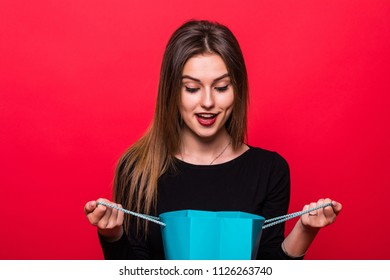 Excited And Surprise For Beautiful Young Woman Opening Gift Bag With Present Isolated On Red