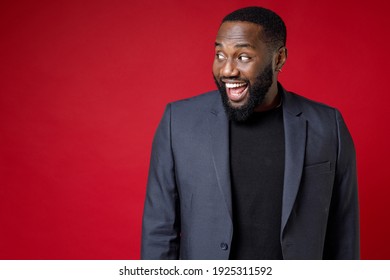 Excited Surprised Amazed Young African American Business Man 20s Wearing Classic Jacket Suit Standing Keeping Mouth Open Looking Aside Isolated On Bright Red Color Wall Background Studio Portrait