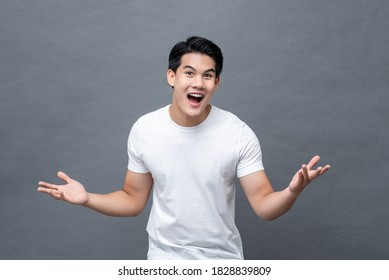 Excited surprised handsome young Asian man in open hand gesture isolated on light gray background - Powered by Shutterstock