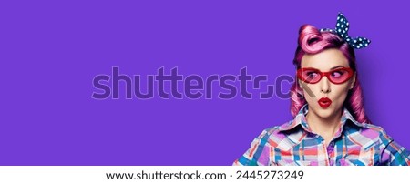 Excited surprised woman. Pinup girl  wear red glasses look sideways. Purple head model at retro fashion vintage advertisement concept. Isolated violet background with empty ad text place. Wide banner.