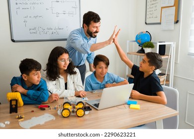 Excited teacher and teen student doing a high five celebrating finishing an electronic robotic project  - Powered by Shutterstock