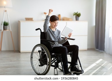 Excited Teen Boy In Wheelchair Holding Tablet Computer, Celebrating His Achievement Or Success, Winning Lottery At Home