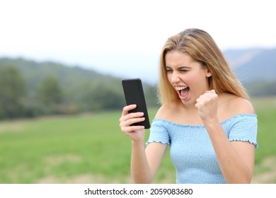 Excited Teen Checking Online Content On Smart Phone In A Field