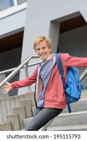 Excited Teenage Boy Sliding Down Handrail On University Stairway