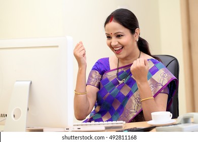 Excited traditional Indian business woman at office desk