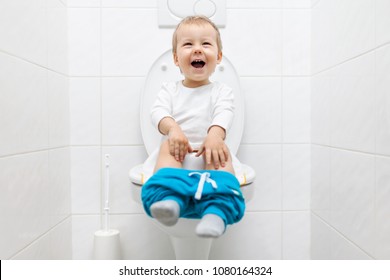 Excited Two Year Old Toddler Sitting On Toilet With Pants Down