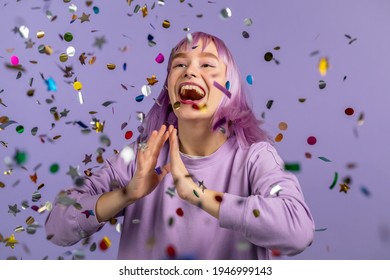 Excited unique woman clapping hands, having fun, screaming WOW, rejoices over confetti rain in studio. Extraordinary girl with very peri dyed hairstyle. Concept of celebrating, party, winning