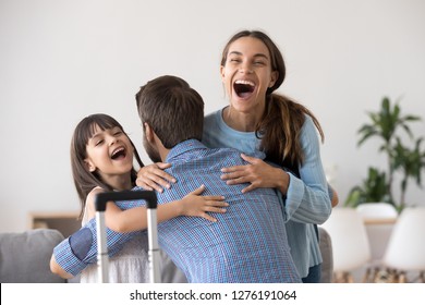 Excited Wife And Kid Daughter Hugging Father Arriving Returning After Long Trip With Suitcase, Happy Dad Embracing Surprised Loving Family Welcoming Missing Daddy Coming Back Home, Reunion Concept