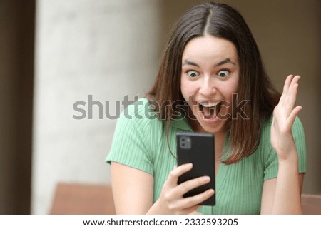 Excited woman checking amazing content on phone in the street
