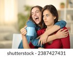 Excited woman embracing a perplexed friend at home