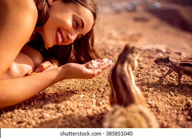Excited woman feeding moorish squirrel on Fuerventura island in Spain